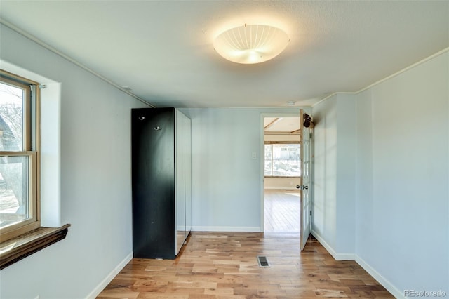 empty room featuring baseboards, visible vents, and light wood-style flooring