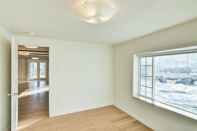 unfurnished room featuring baseboards, light wood-style floors, and french doors