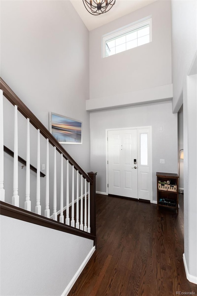 entrance foyer with a towering ceiling, a chandelier, and dark hardwood / wood-style flooring