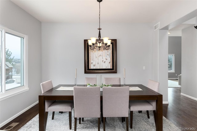 dining room with a healthy amount of sunlight, dark hardwood / wood-style floors, and an inviting chandelier