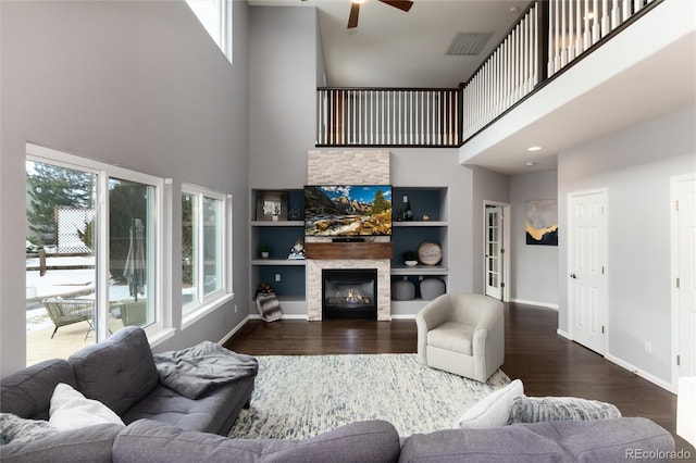 living room with built in features, hardwood / wood-style flooring, a towering ceiling, and a wealth of natural light