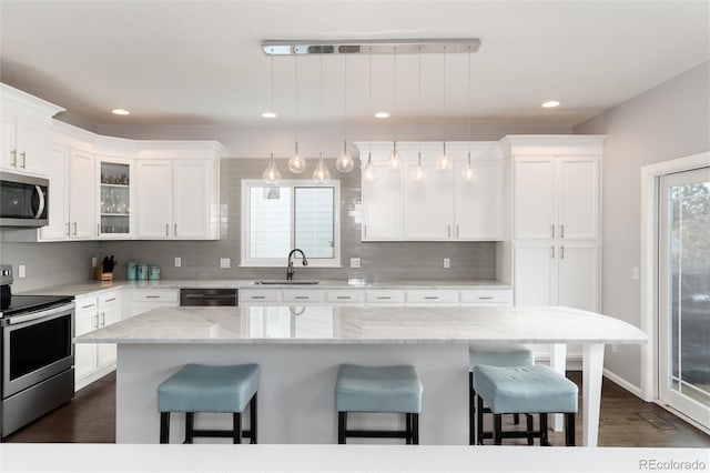 kitchen featuring hanging light fixtures, sink, a kitchen island, a breakfast bar, and stainless steel appliances