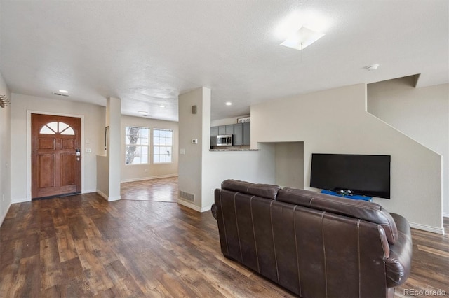 living area featuring dark wood-style floors, visible vents, and baseboards