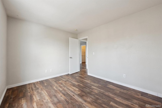 unfurnished room with dark wood-type flooring and baseboards