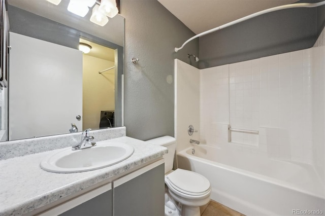 bathroom with a textured wall, bathtub / shower combination, toilet, vanity, and washer / dryer