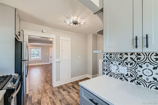 kitchen with light stone countertops, wood-type flooring, and stainless steel appliances