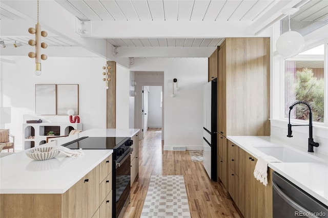 kitchen featuring a sink, stainless steel dishwasher, freestanding refrigerator, black electric range oven, and beamed ceiling