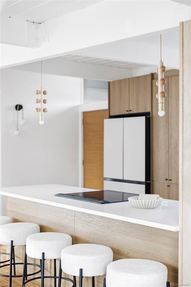 interior space with hanging light fixtures, a breakfast bar area, and freestanding refrigerator