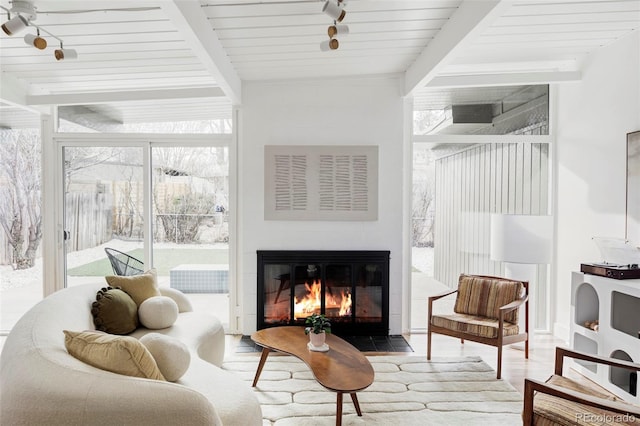 sitting room featuring a fireplace with flush hearth, expansive windows, beam ceiling, and wood finished floors