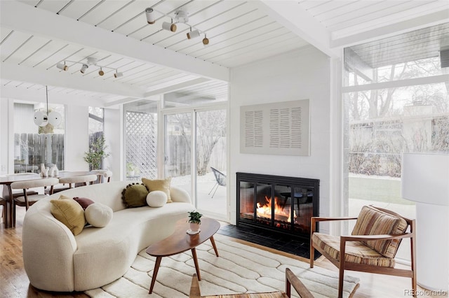 sunroom featuring a fireplace with flush hearth, track lighting, a wealth of natural light, and beamed ceiling