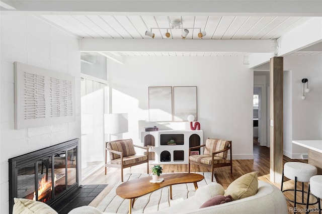 living area with lofted ceiling with beams, a fireplace, wood finished floors, wood ceiling, and baseboards