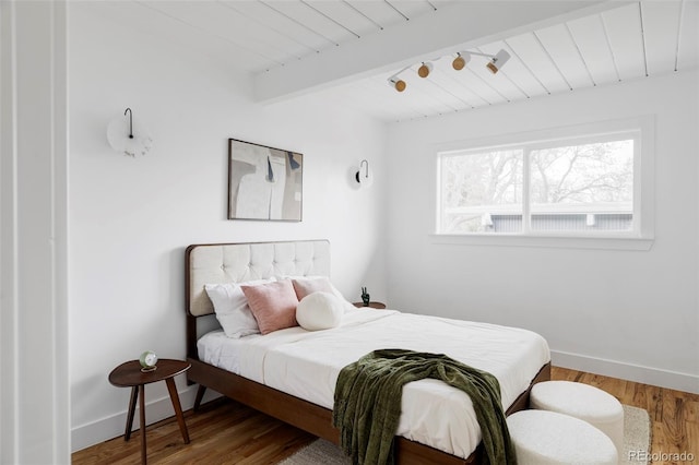 bedroom with wood ceiling, beamed ceiling, baseboards, and wood finished floors