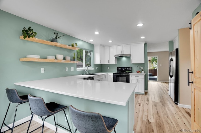 2140 W 135th Ave, Westminster, CO 80234 - kitchen featuring black appliances, a peninsula, light wood finished floors, under cabinet range hood, and a kitchen bar