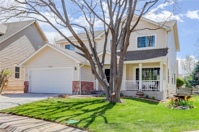 view of front of property with roof with shingles, an attached garage, a front yard, covered porch, and driveway