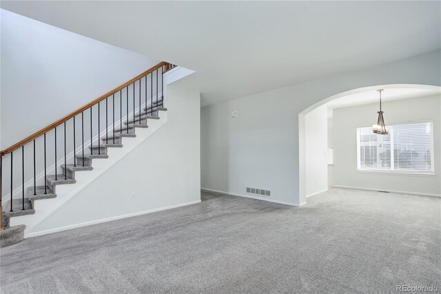 unfurnished living room featuring visible vents, stairs, baseboards, arched walkways, and carpet
