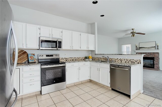 kitchen with a sink, light stone countertops, stainless steel appliances, and a peninsula