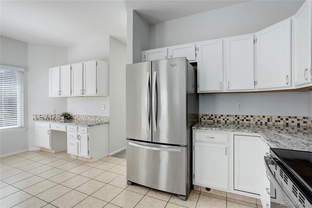 kitchen featuring light stone counters, freestanding refrigerator, and white cabinets