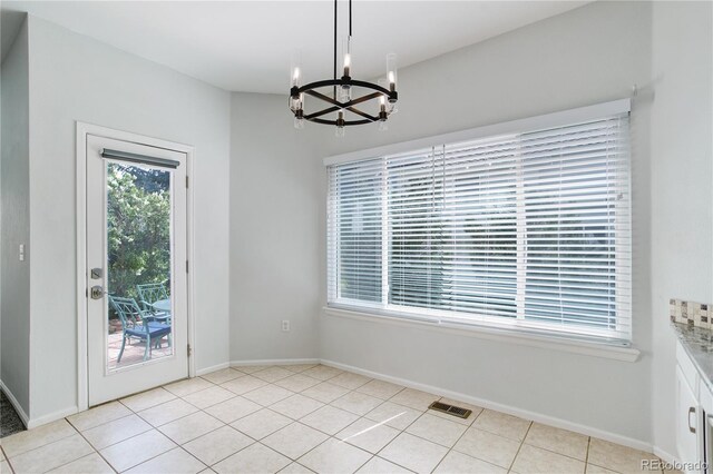 unfurnished dining area with baseboards, a notable chandelier, light tile patterned floors, and visible vents