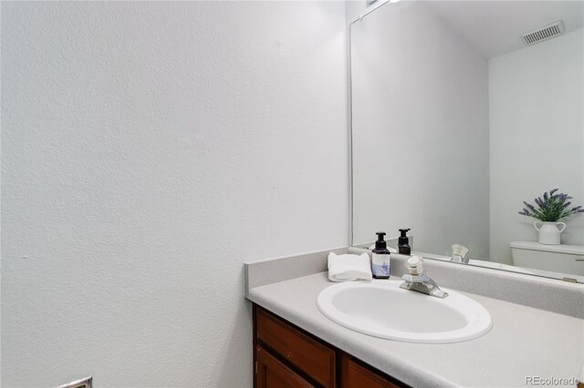 bathroom featuring visible vents, toilet, and vanity