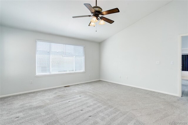 carpeted empty room featuring baseboards, a ceiling fan, and vaulted ceiling