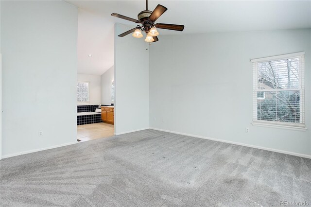 empty room featuring ceiling fan, light colored carpet, baseboards, and lofted ceiling