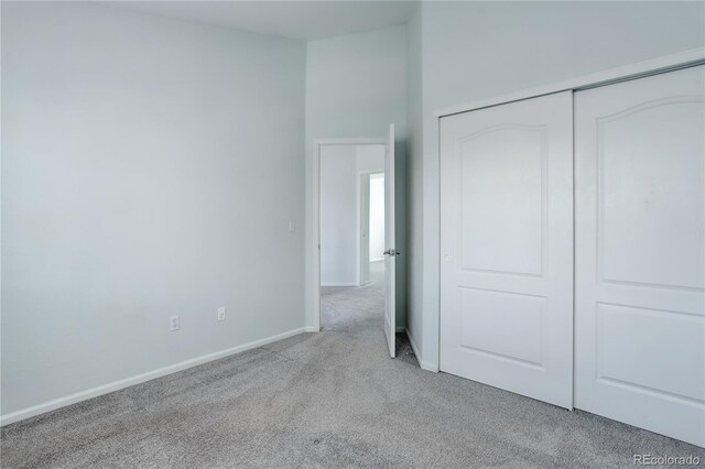 unfurnished bedroom featuring baseboards, carpet, and a closet