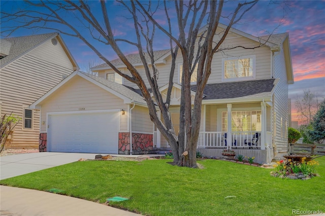 traditional-style home featuring a shingled roof, an attached garage, a front yard, covered porch, and driveway