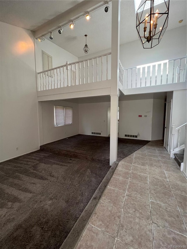 15983 E Loyola Dr, Aurora, CO 80013 - unfurnished living room with an inviting chandelier, tile patterned floors, carpet, and a towering ceiling