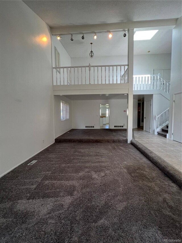15983 E Loyola Dr, Aurora, CO 80013 - unfurnished living room featuring stairway, carpet floors, a towering ceiling, and visible vents
