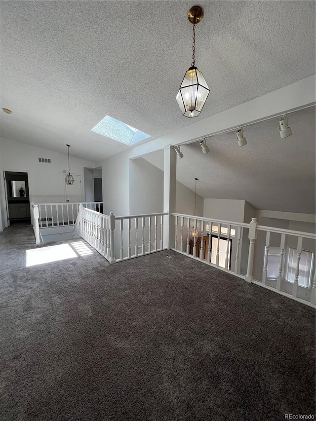 15983 E Loyola Dr, Aurora, CO 80013 - carpeted empty room featuring vaulted ceiling with skylight, track lighting, a textured ceiling, and visible vents