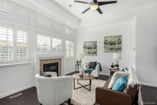 living room featuring a tile fireplace, dark hardwood / wood-style floors, and a wealth of natural light