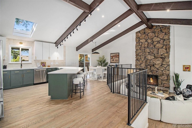 14890 W 58th Pl, Golden, CO 80403 - kitchen with stainless steel dishwasher, open floor plan, light wood finished floors, and light countertops