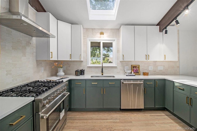 14890 W 58th Pl, Golden, CO 80403 - kitchen featuring stainless steel appliances, green cabinetry, wall chimney range hood, and white cabinets