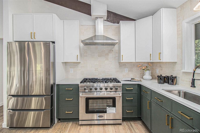 14890 W 58th Pl, Golden, CO 80403 - kitchen with stainless steel appliances, green cabinets, white cabinetry, light countertops, and wall chimney exhaust hood