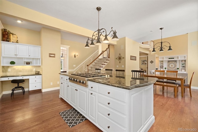 kitchen featuring stainless steel gas cooktop, hanging light fixtures, a kitchen island, and white cabinets