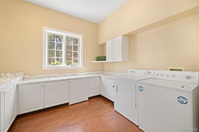 laundry room featuring light hardwood / wood-style flooring, washer and clothes dryer, and cabinets