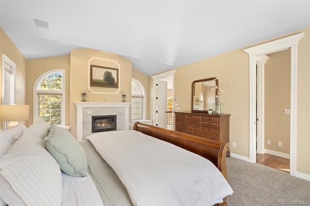 bedroom with lofted ceiling, carpet floors, and a fireplace