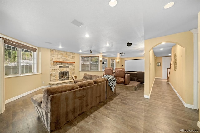 living room with a stone fireplace, light hardwood / wood-style flooring, a textured ceiling, and a healthy amount of sunlight