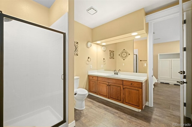 bathroom featuring vanity, hardwood / wood-style floors, a shower with shower door, and toilet