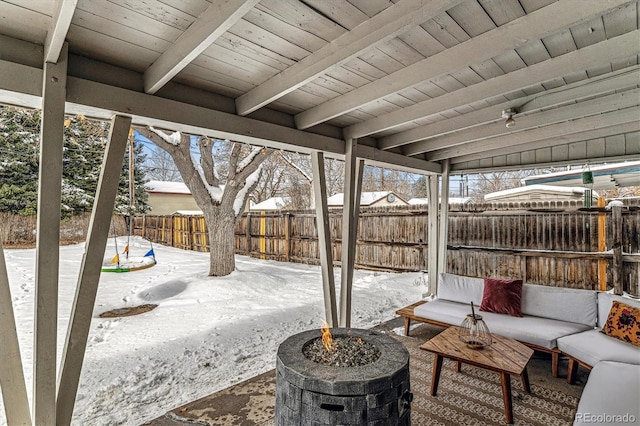 snow covered patio featuring an outdoor fire pit and fence