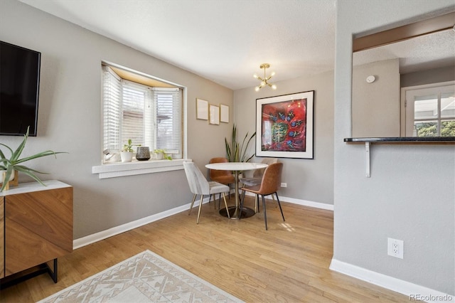 dining space featuring baseboards, a notable chandelier, and wood finished floors