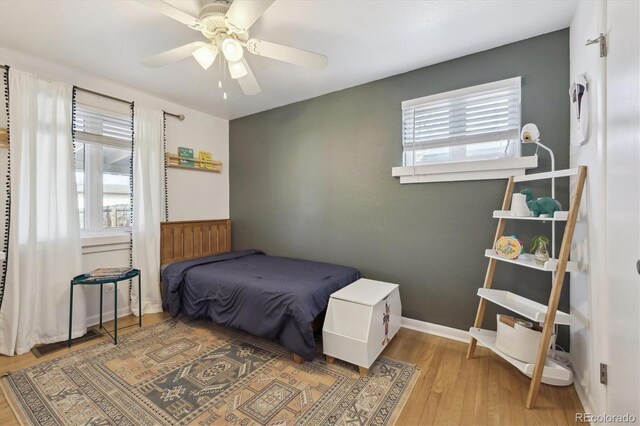 bedroom with a ceiling fan, wood finished floors, and baseboards