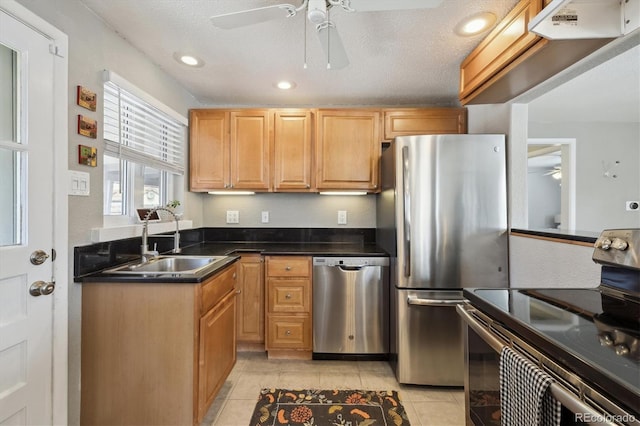 kitchen featuring a sink, dark countertops, stainless steel appliances, light tile patterned flooring, and ceiling fan