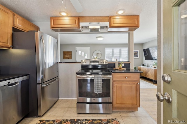 kitchen featuring a textured ceiling, dark countertops, light tile patterned floors, and stainless steel appliances