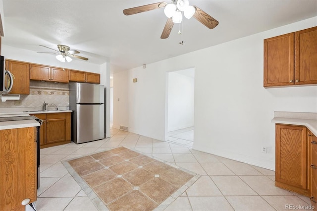 kitchen with stainless steel appliances, a ceiling fan, and brown cabinetry