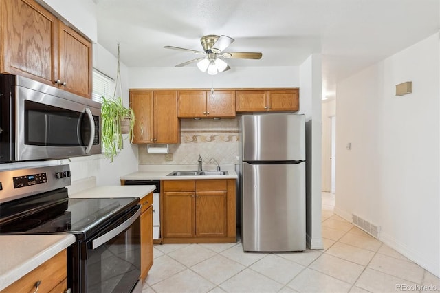 kitchen with stainless steel appliances, a sink, ceiling fan, light countertops, and tasteful backsplash