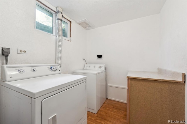 washroom with washing machine and clothes dryer and light wood finished floors