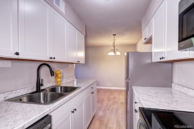 kitchen featuring white cabinets, a notable chandelier, and sink