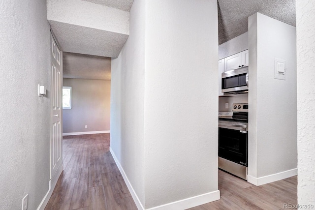 hall with light hardwood / wood-style flooring and a textured ceiling