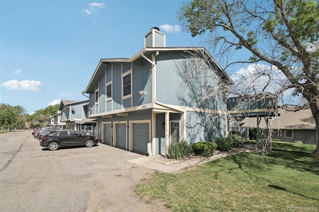 12115 Bannock St Unit B, Denver, CO 80234 - view of front of property featuring a chimney, an attached garage, a front lawn, and asphalt driveway